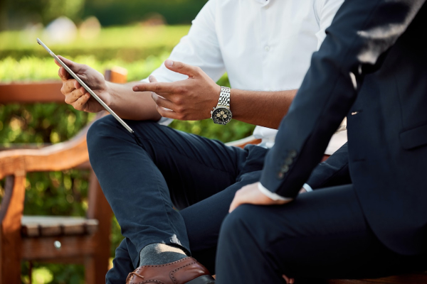 One person showing another person something on a tablet computer